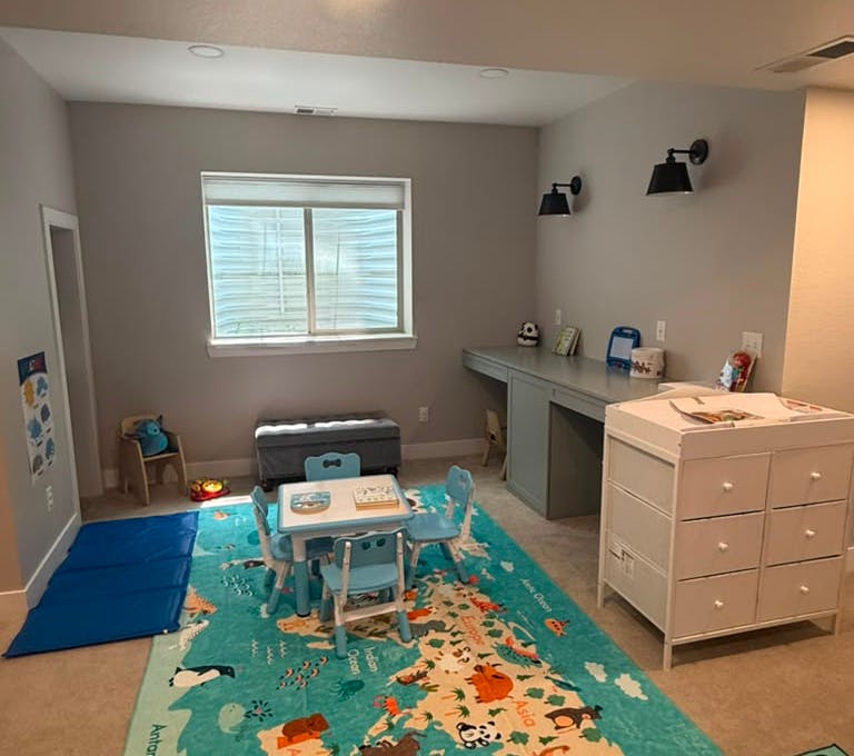 Childs playroom with a small table and chairs on a world map rug