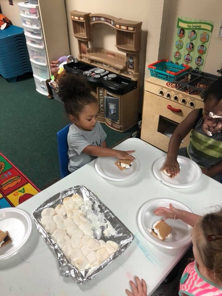 Children making s'mores at a table in a classroom