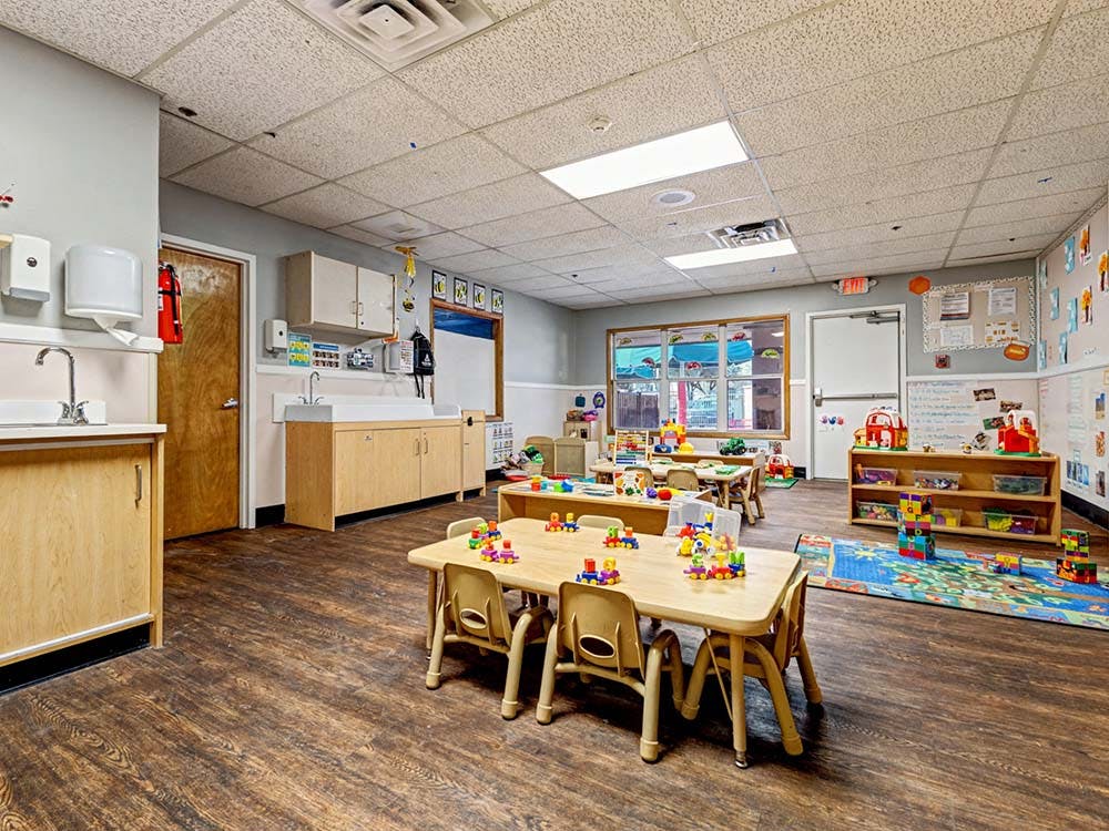 Classroom with small tables, chairs, toys, and sinks