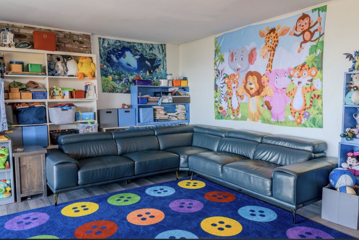 Playroom with a blue sectional sofa and colorful button-patterned rug