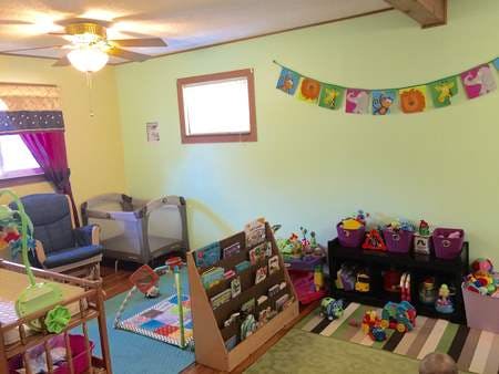 Playroom with cribs, toys, and a bookshelf