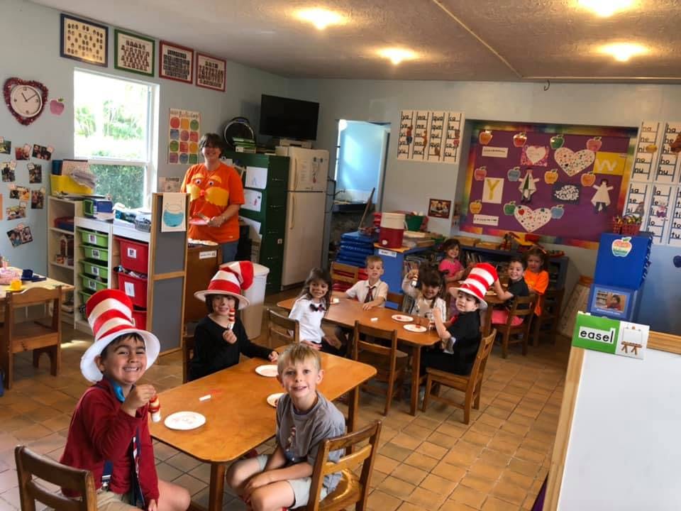Children in Cat in the Hat hats sitting at tables in a classroom