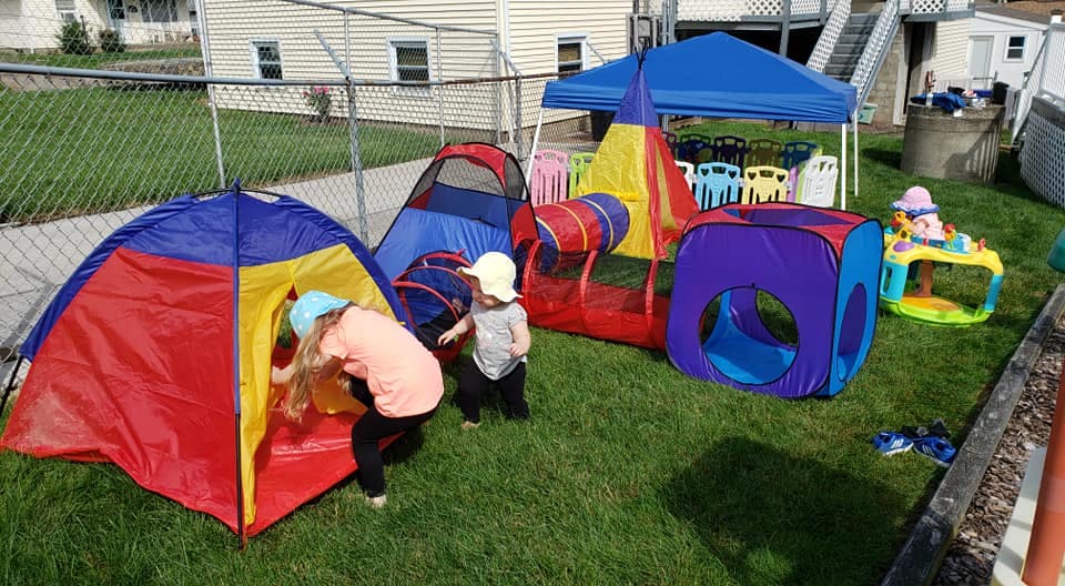 Two children playing with colorful tents and tunnels on grass