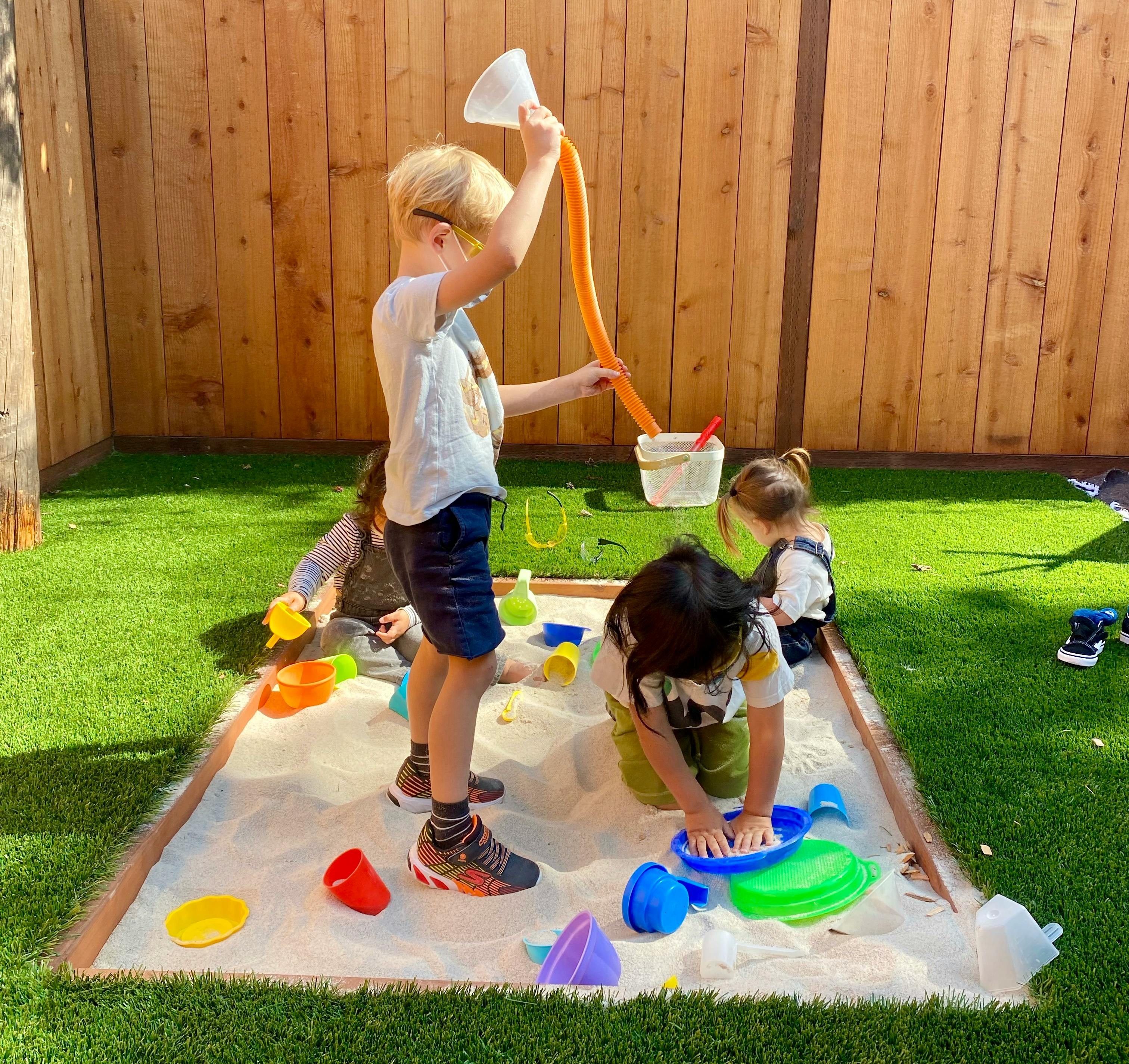 Children playing in a sandbox with sand toys