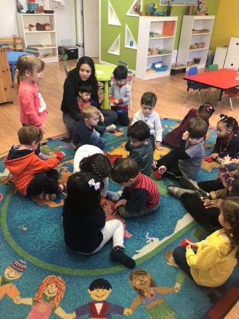 Adult and children sitting on a rug in a classroom