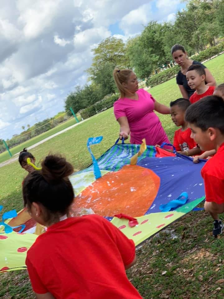 Adults and children playing with a colorful parachute outdoors