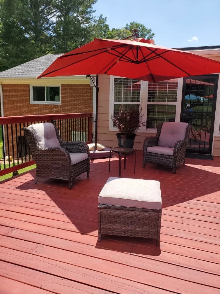 Patio furniture on a red wooden deck under a red umbrella