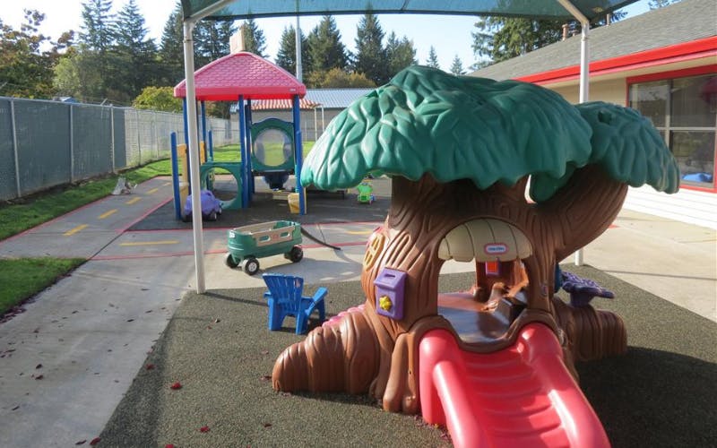 Playground with a tree-shaped slide, blue chair, and wagon