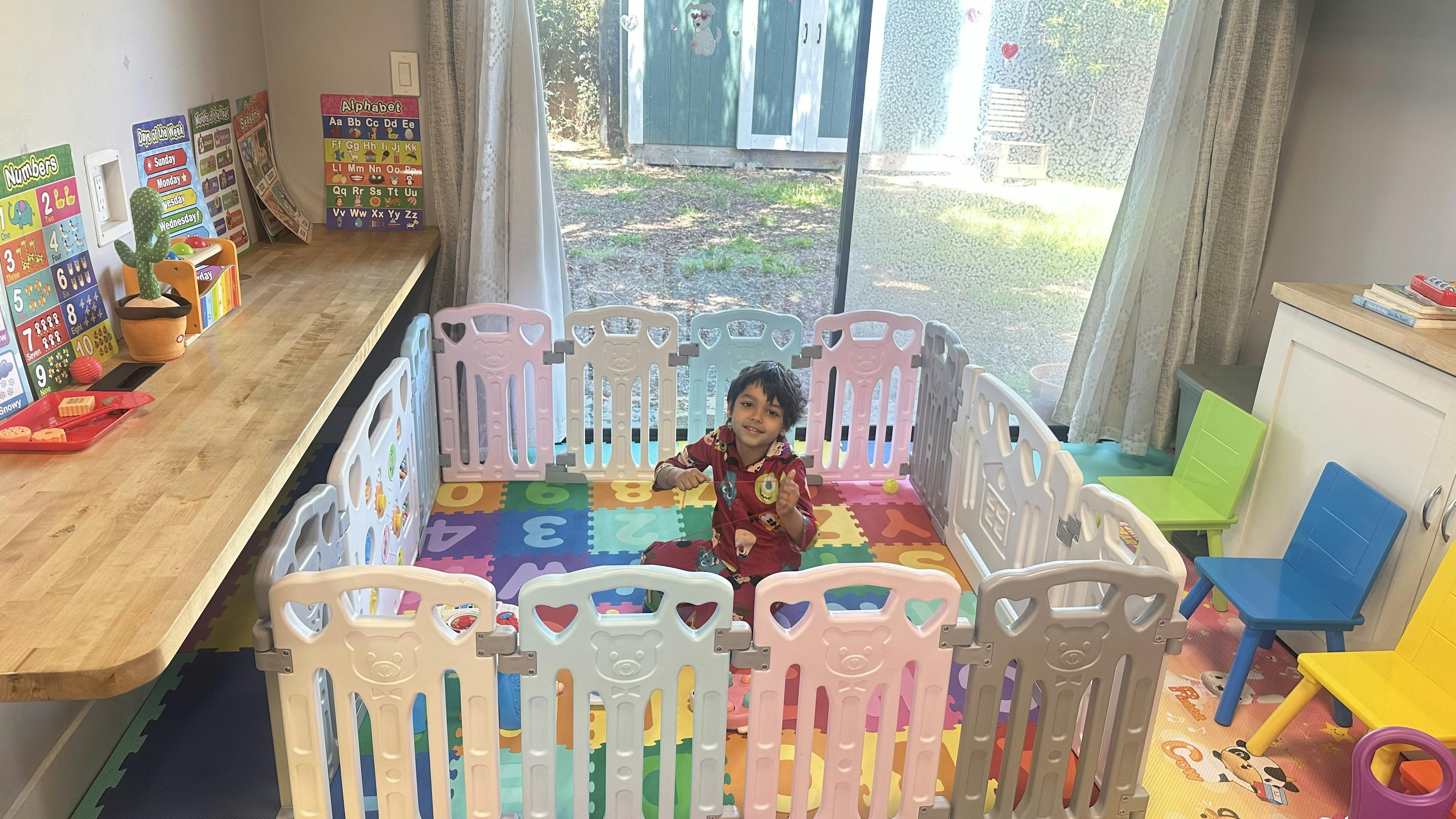 Child sitting in a playpen on a colorful mat