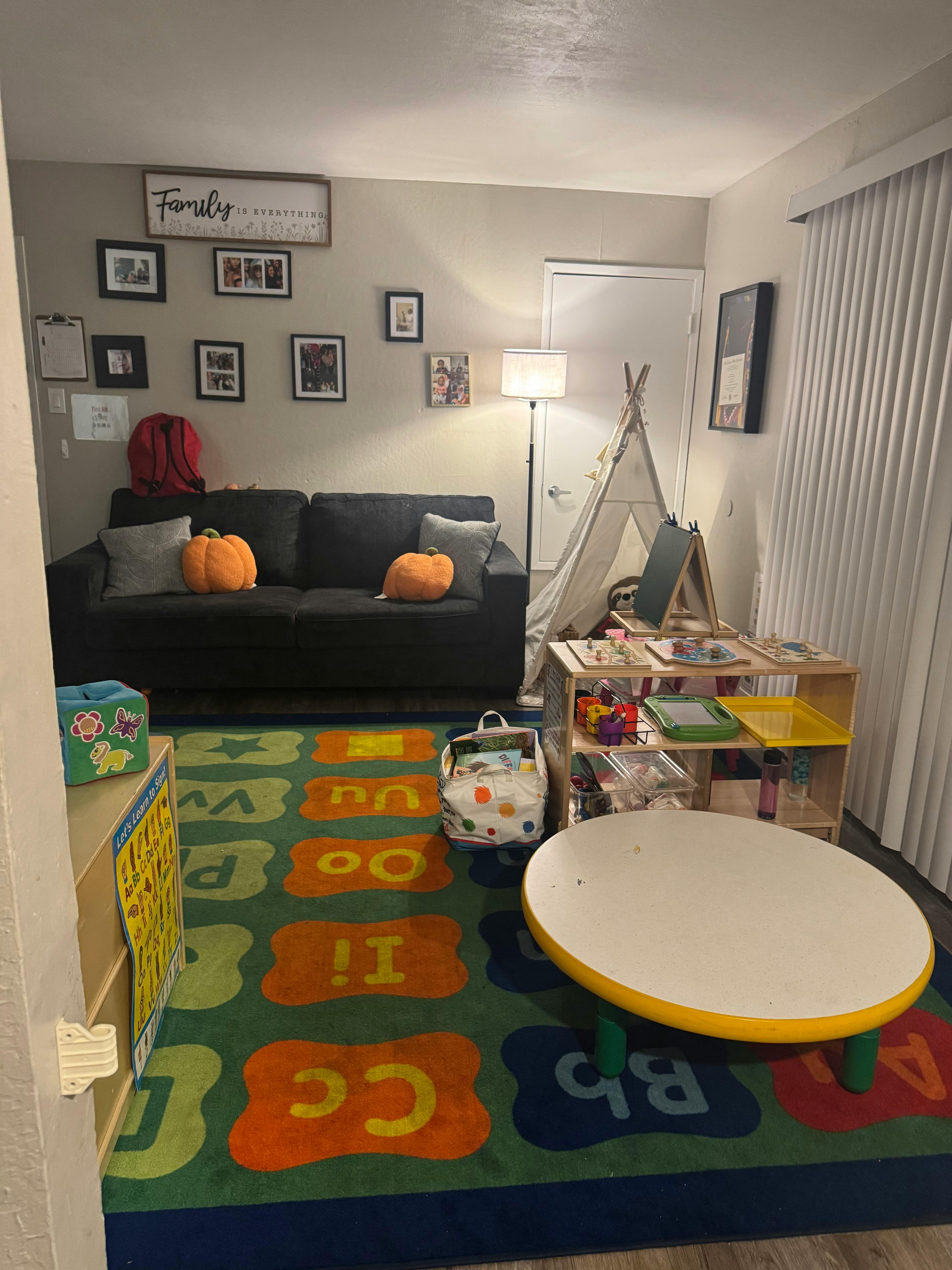 Living room with a sofa, play tent, and a colorful alphabet rug