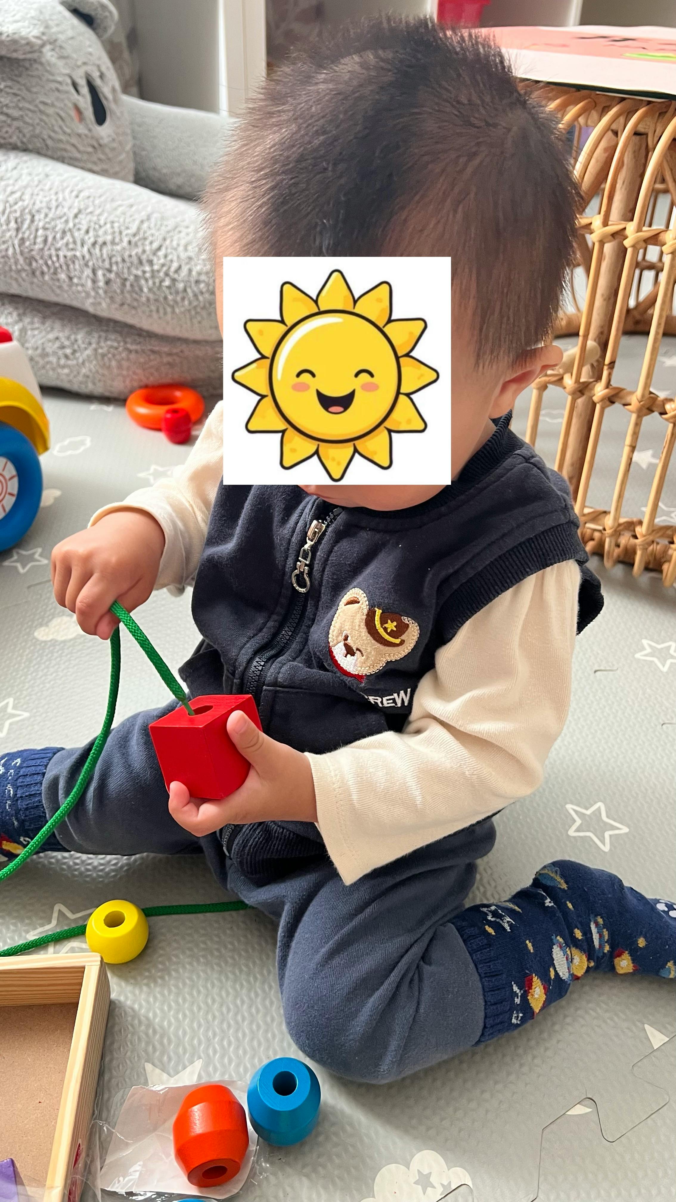 Child playing with a stringing bead toy on a play mat