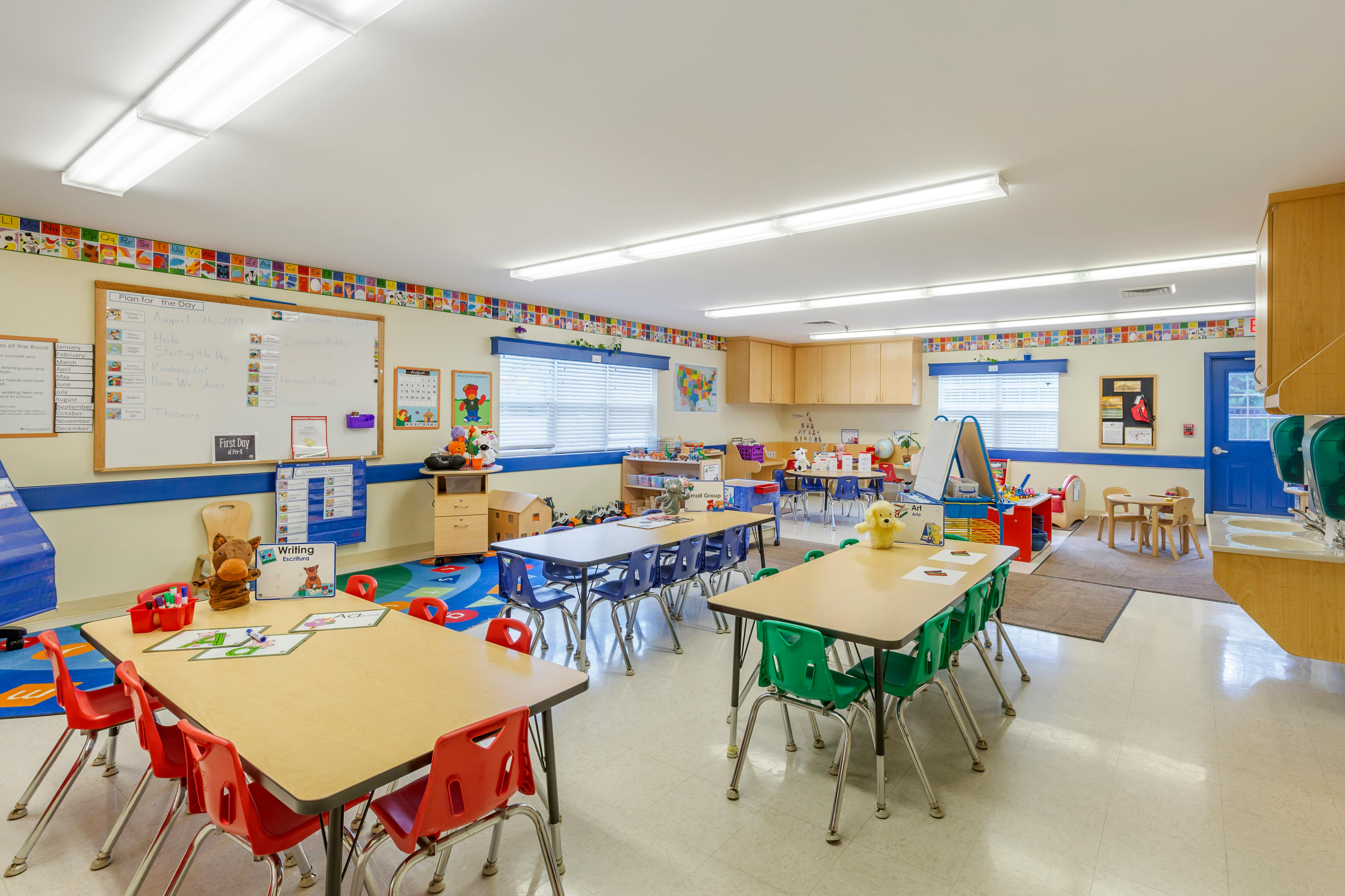 An empty early childhood classroom with multiple tables and chairs