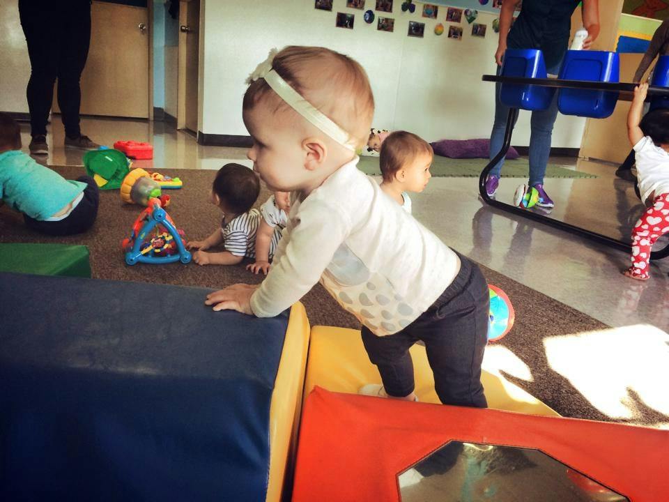 Child crawling on soft play blocks in a room with other children