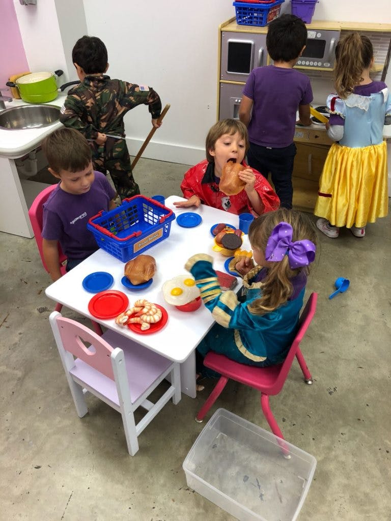 Children playing with toy food at a small table