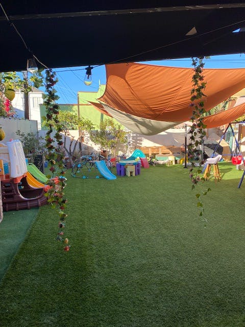 Outdoor play area with artificial turf, slides, and shade sails for children