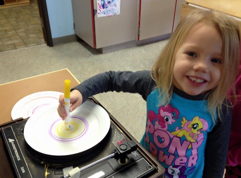 Child drawing on a paper plate on a record player