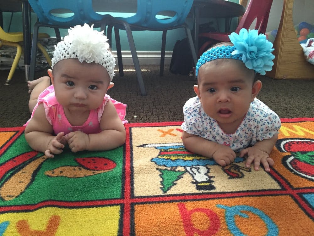 Two babies lying on a colorful rug