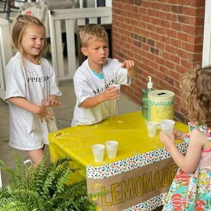 Three children operating a lemonade stand outdoors