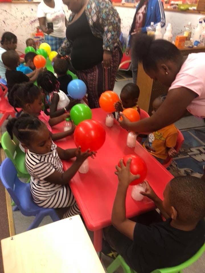 Children and adults at a table with balloons