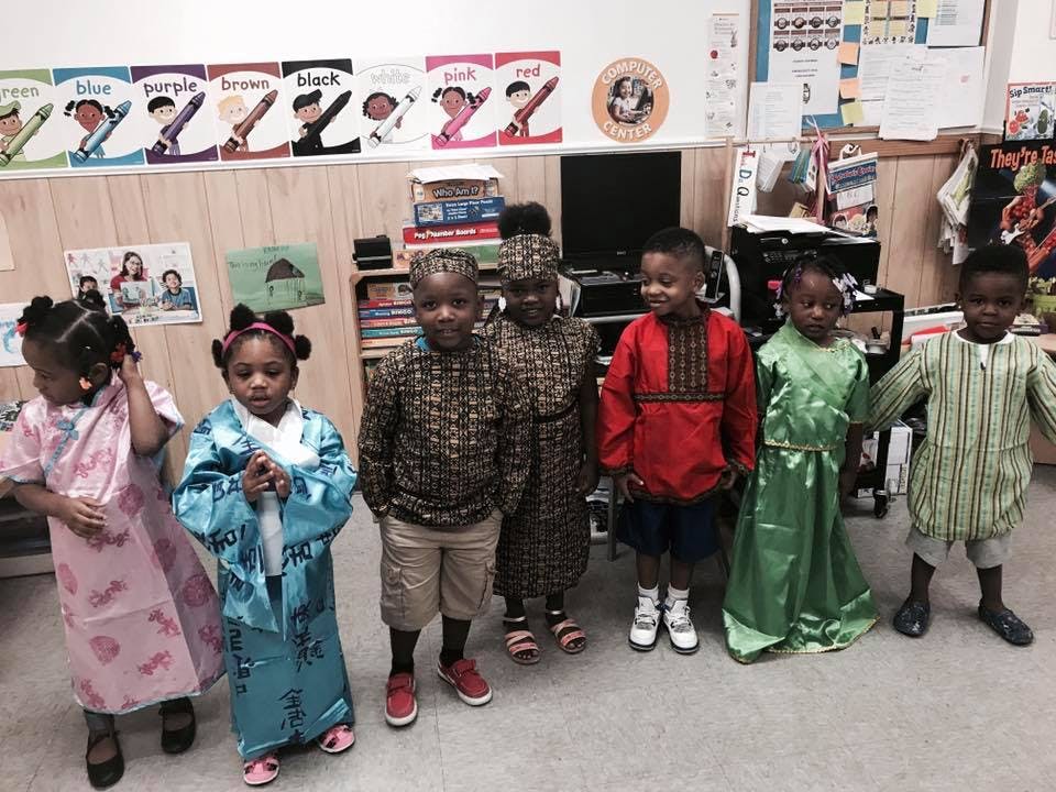 Six children in traditional clothing standing in a classroom