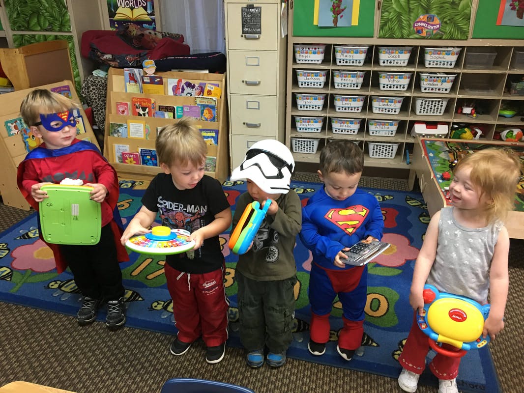 Five children in costumes playing with toys in a room