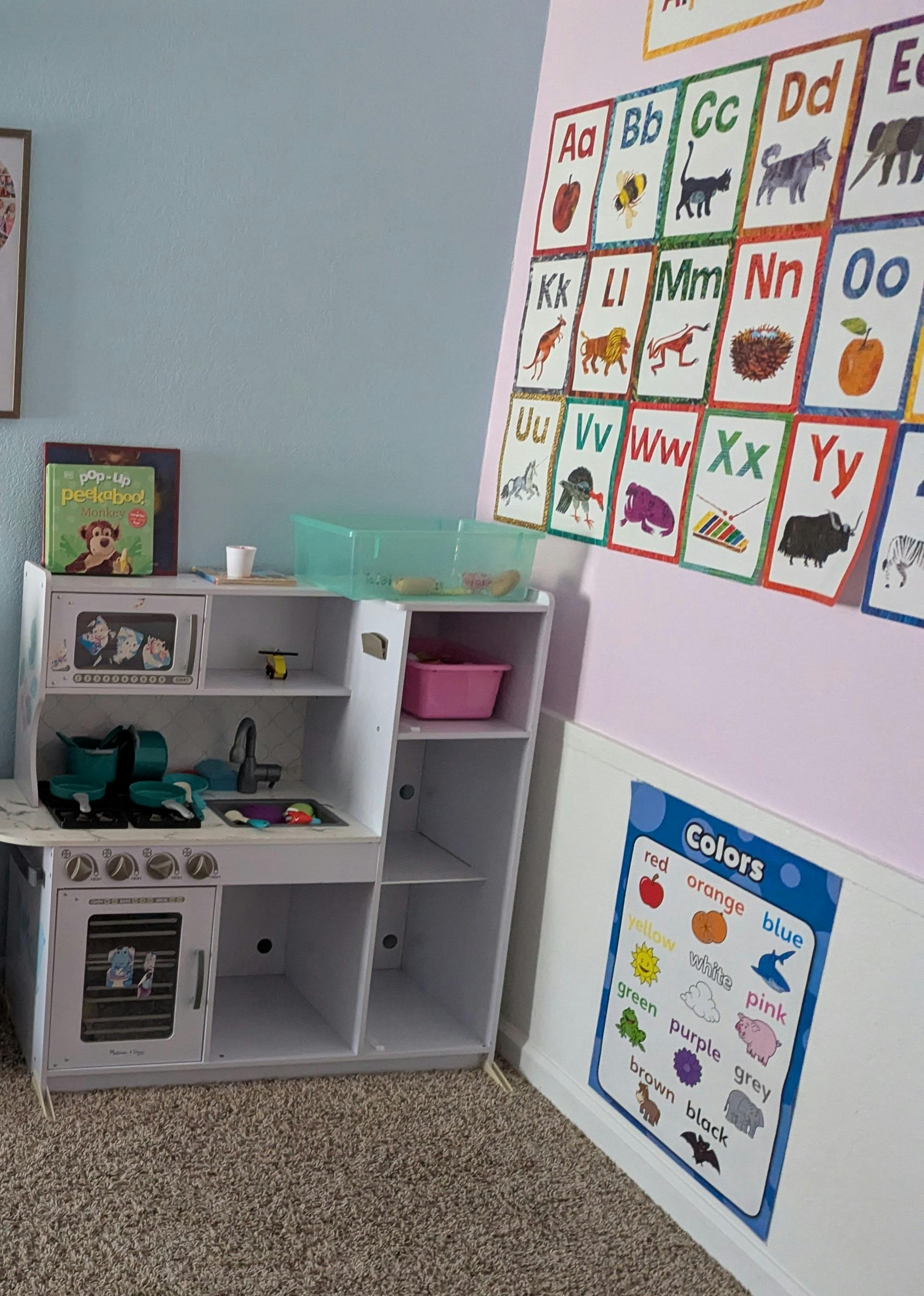 Play kitchen with alphabet and colors charts on the wall
