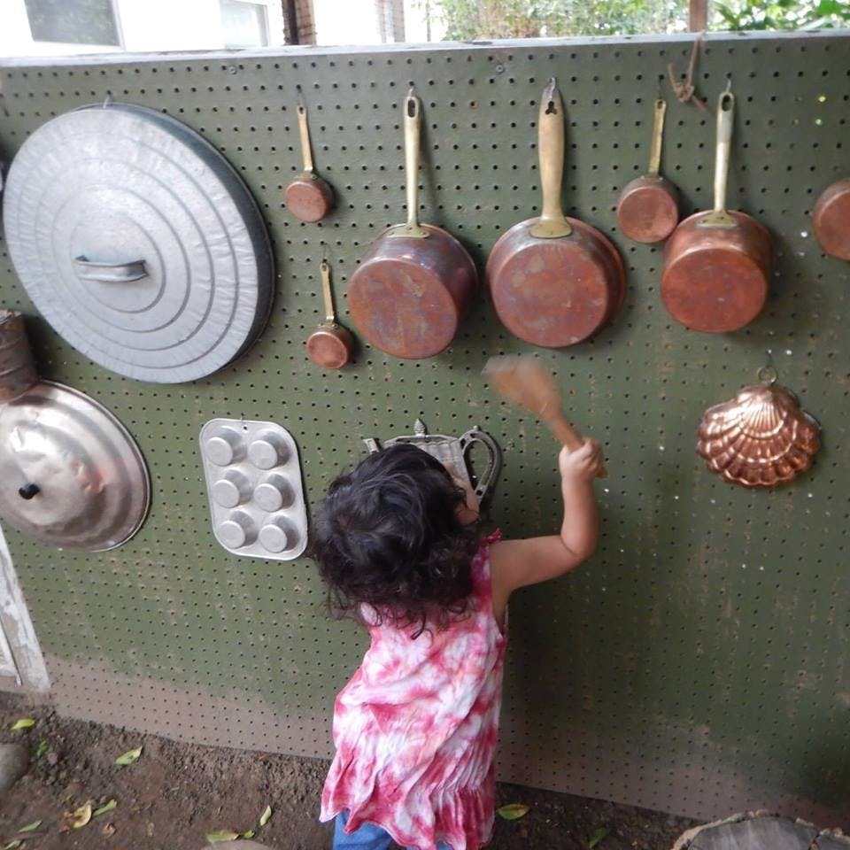 Child playing with pots and pans on a wall
