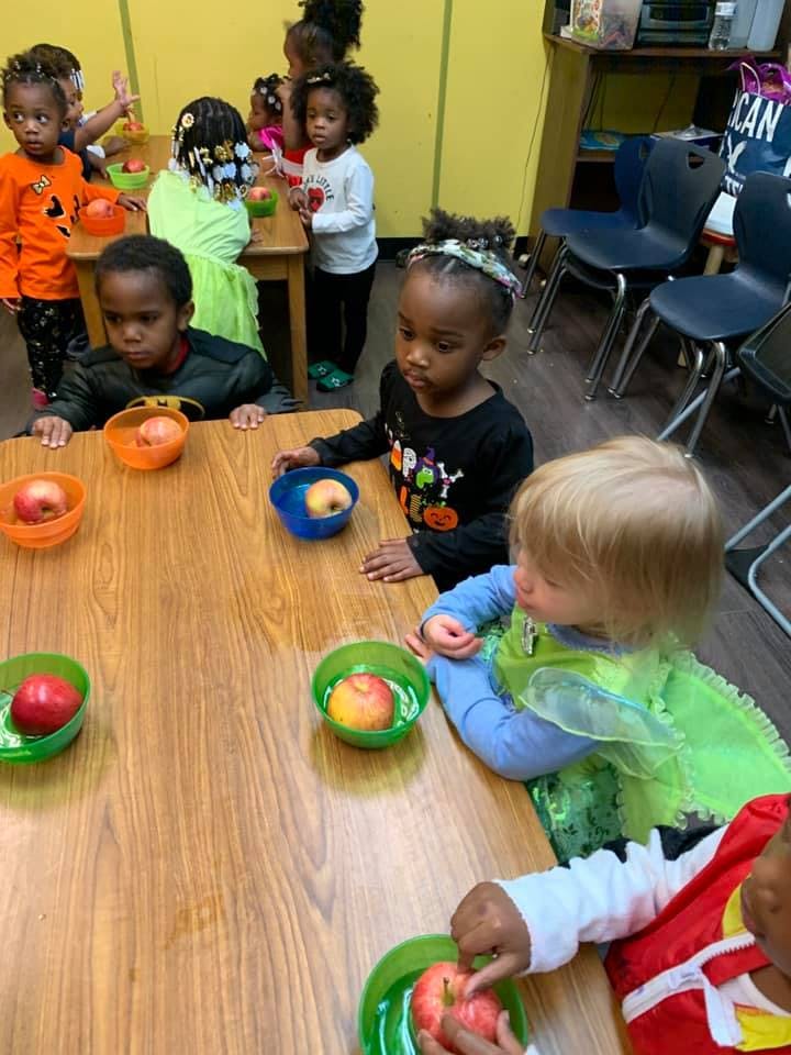 Children sitting at a table with apples in bowls
