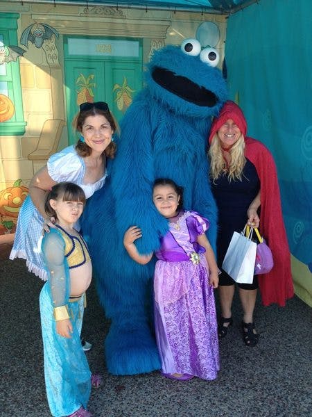 Two adults and two children posing with a Cookie Monster character