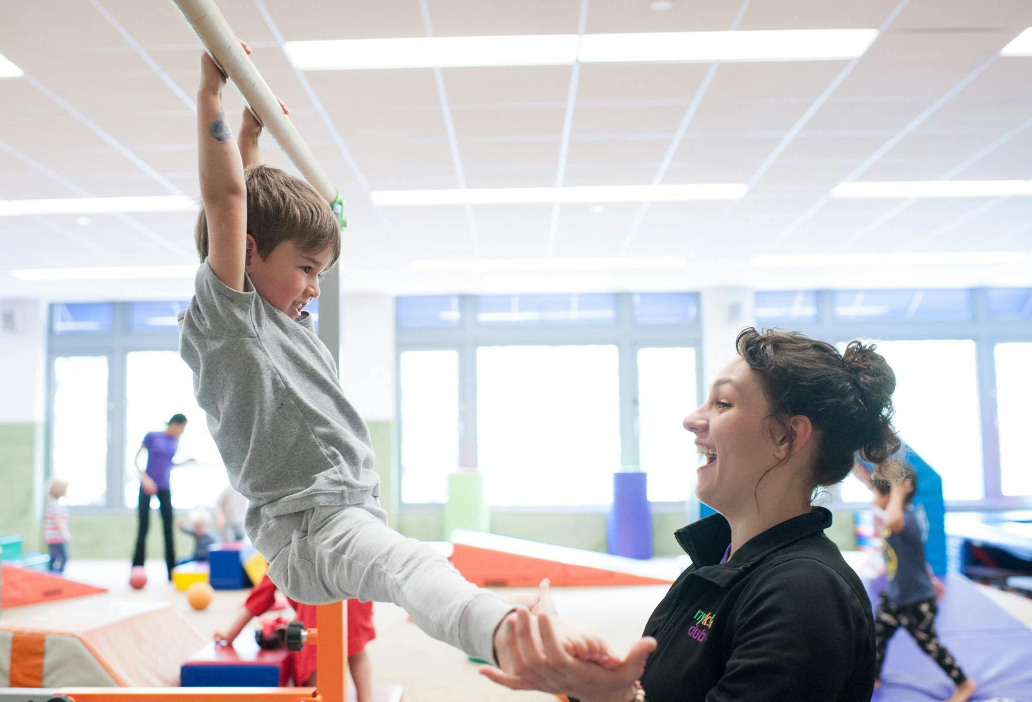 Child on a horizontal bar with a person spotting