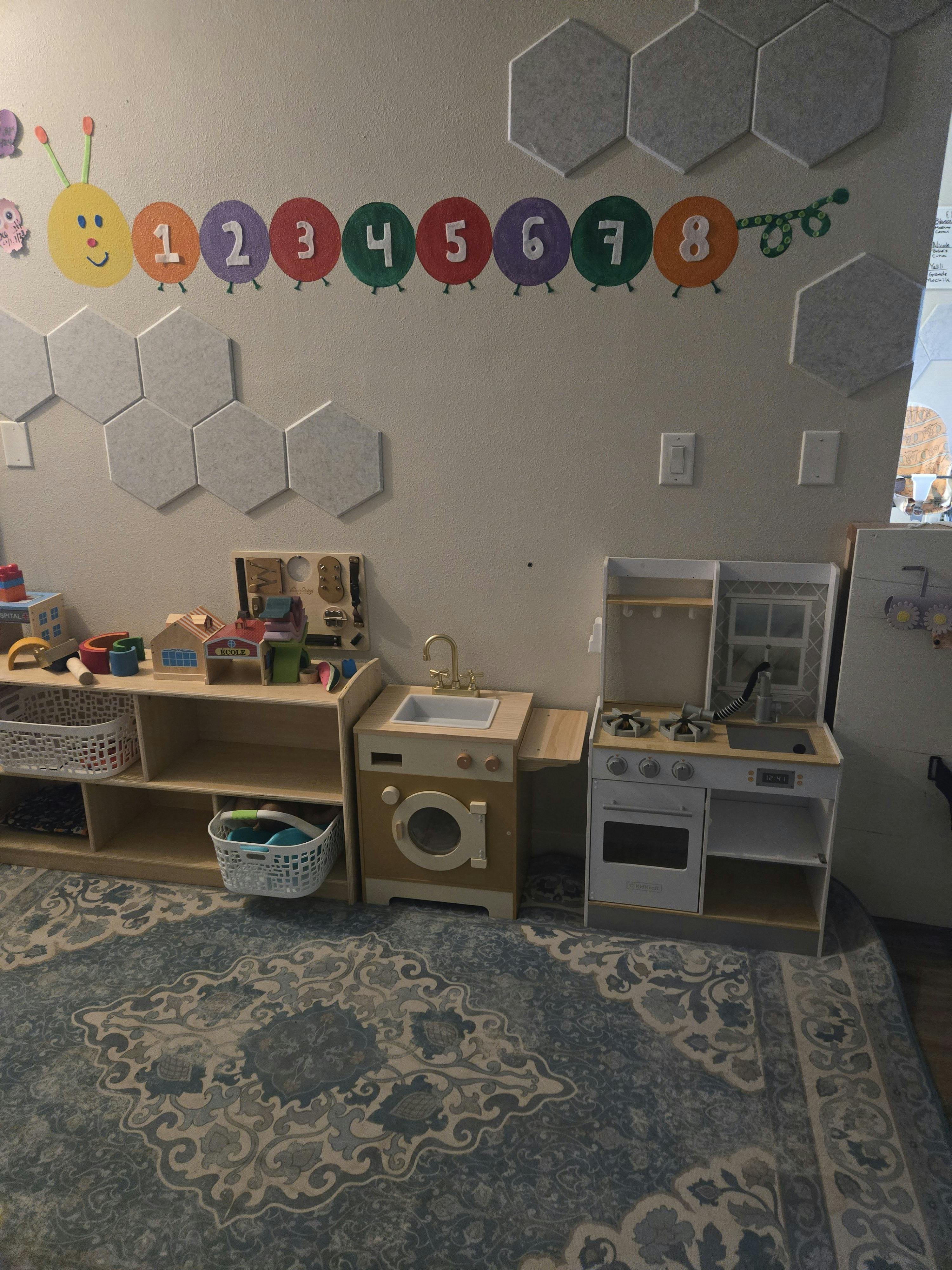 Playroom with a caterpillar counting display on the wall, toy kitchen and laundry