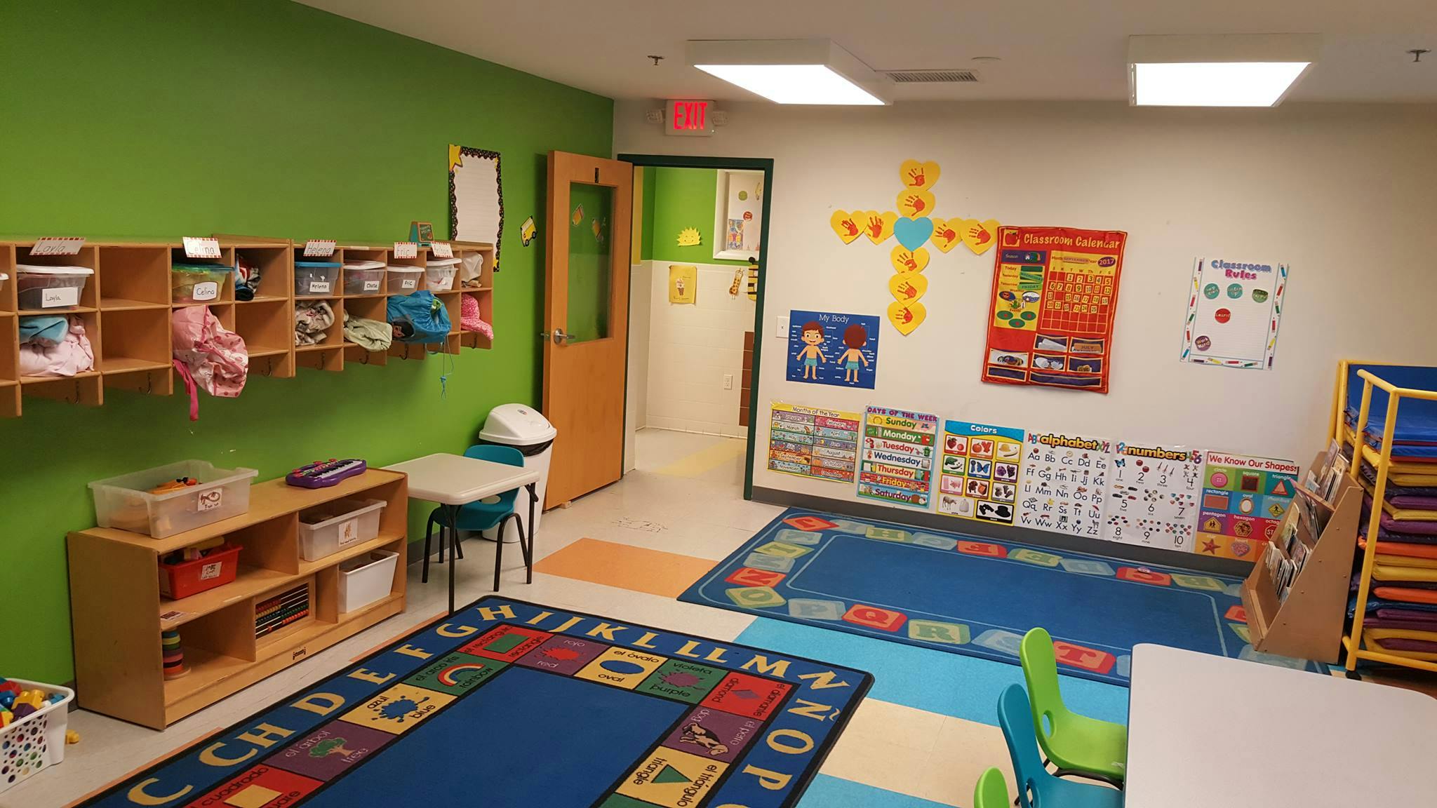 Classroom with colorful rugs, shelves, and educational posters