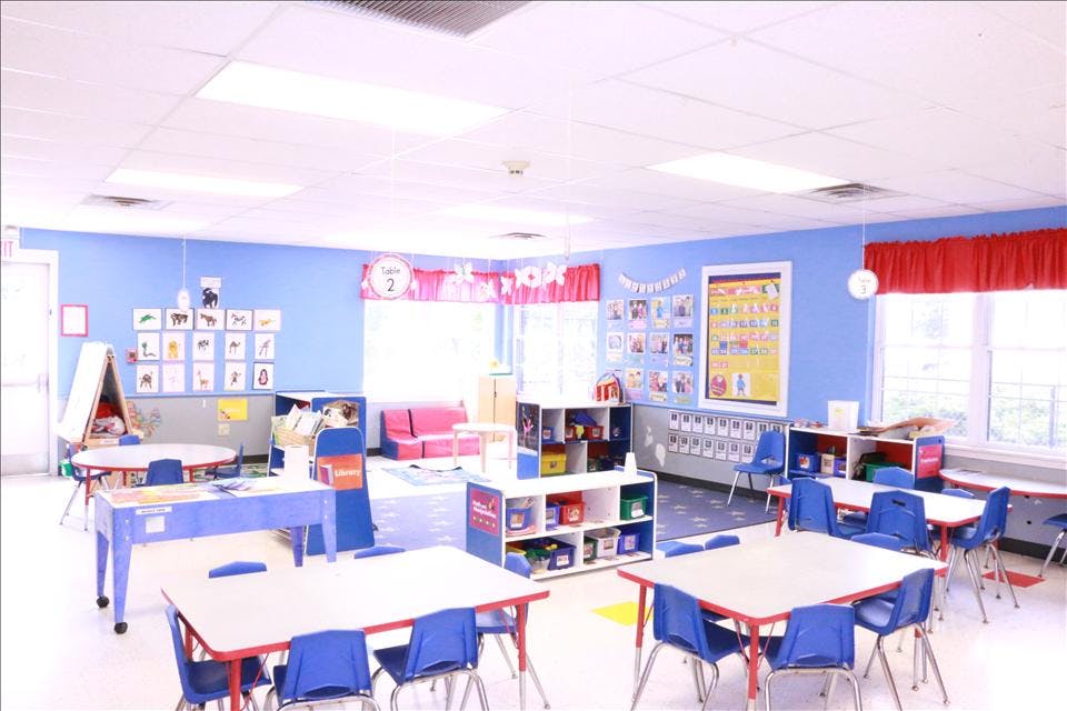 Classroom with blue walls, small tables, chairs, and colorful decorations