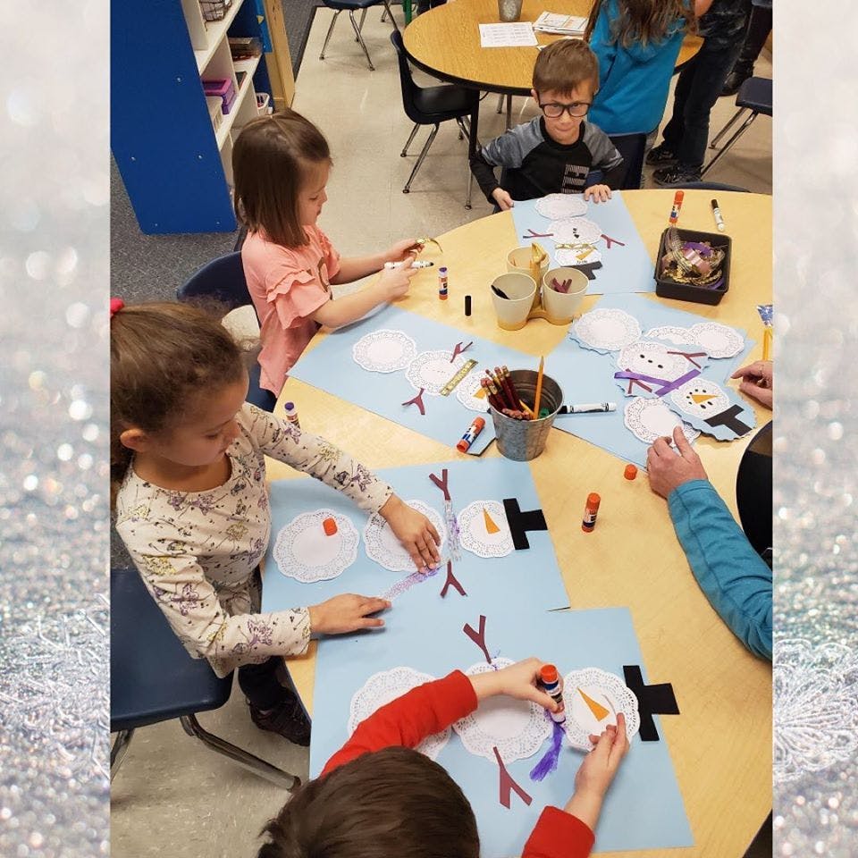 Children making snowman crafts at a table