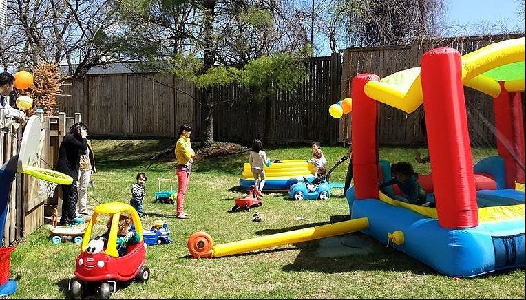 Children playing in a backyard with inflatable bounce houses and toys
