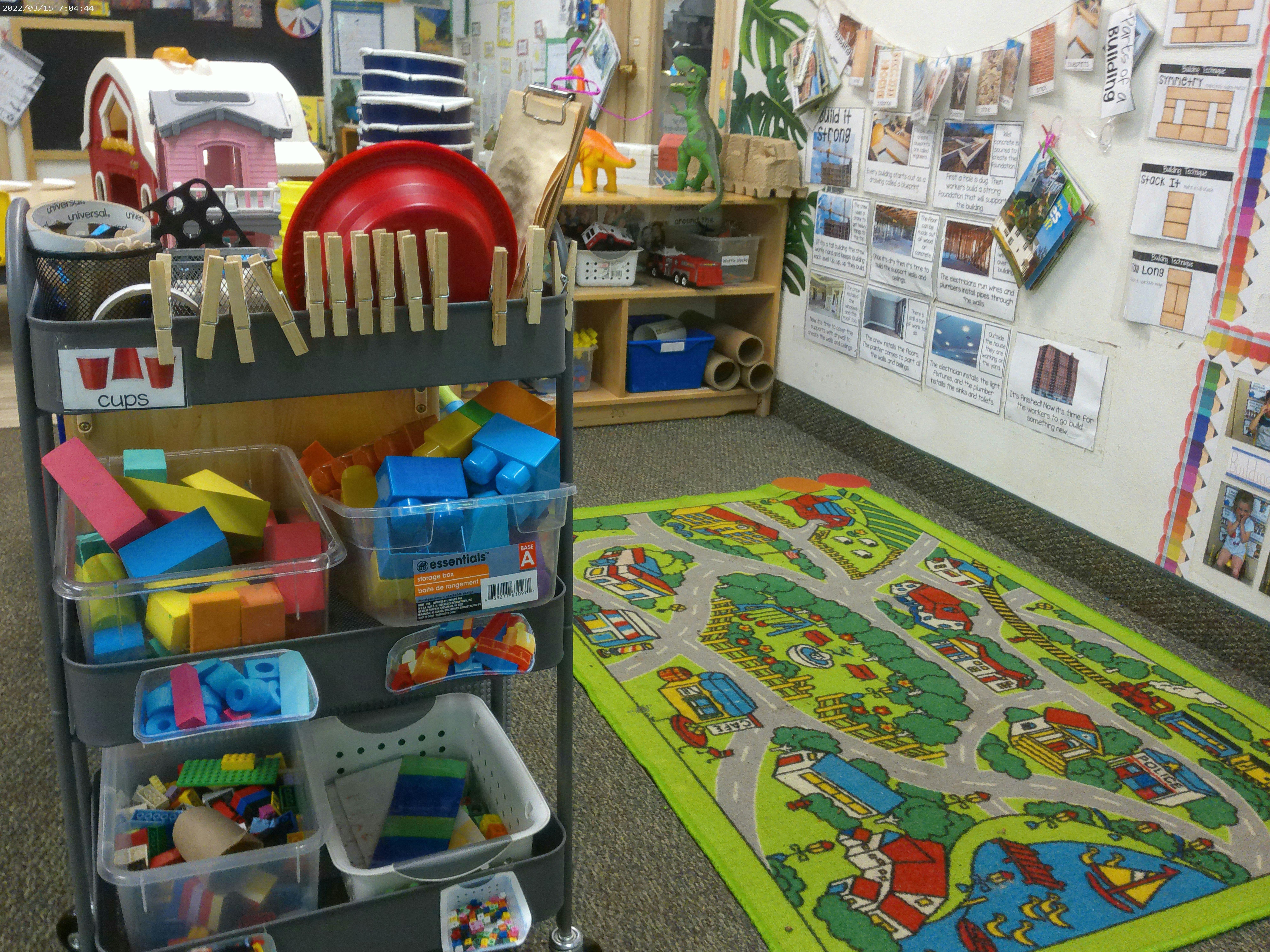 Playroom with a rolling cart full of toys and a green playmat on the floor
