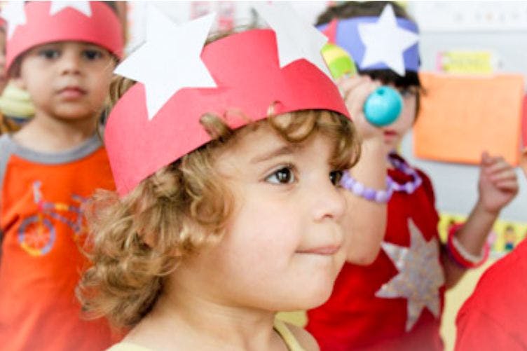 Child wearing a red paper crown with white stars