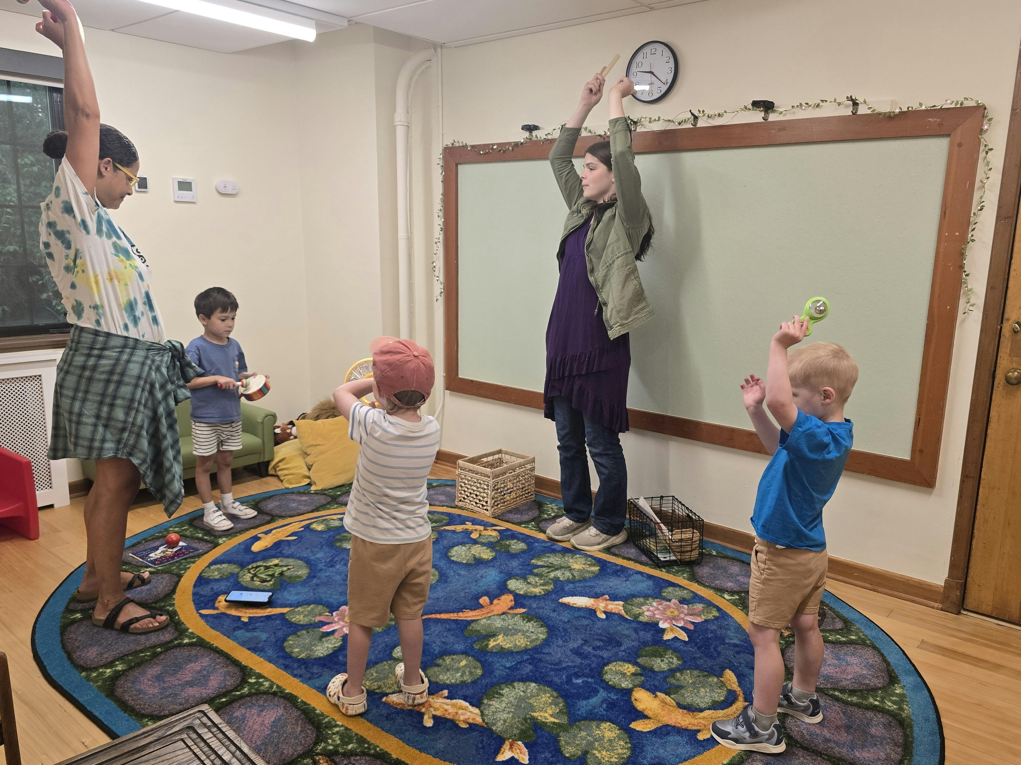 People standing in a circle on a rug playing with small musical instruments