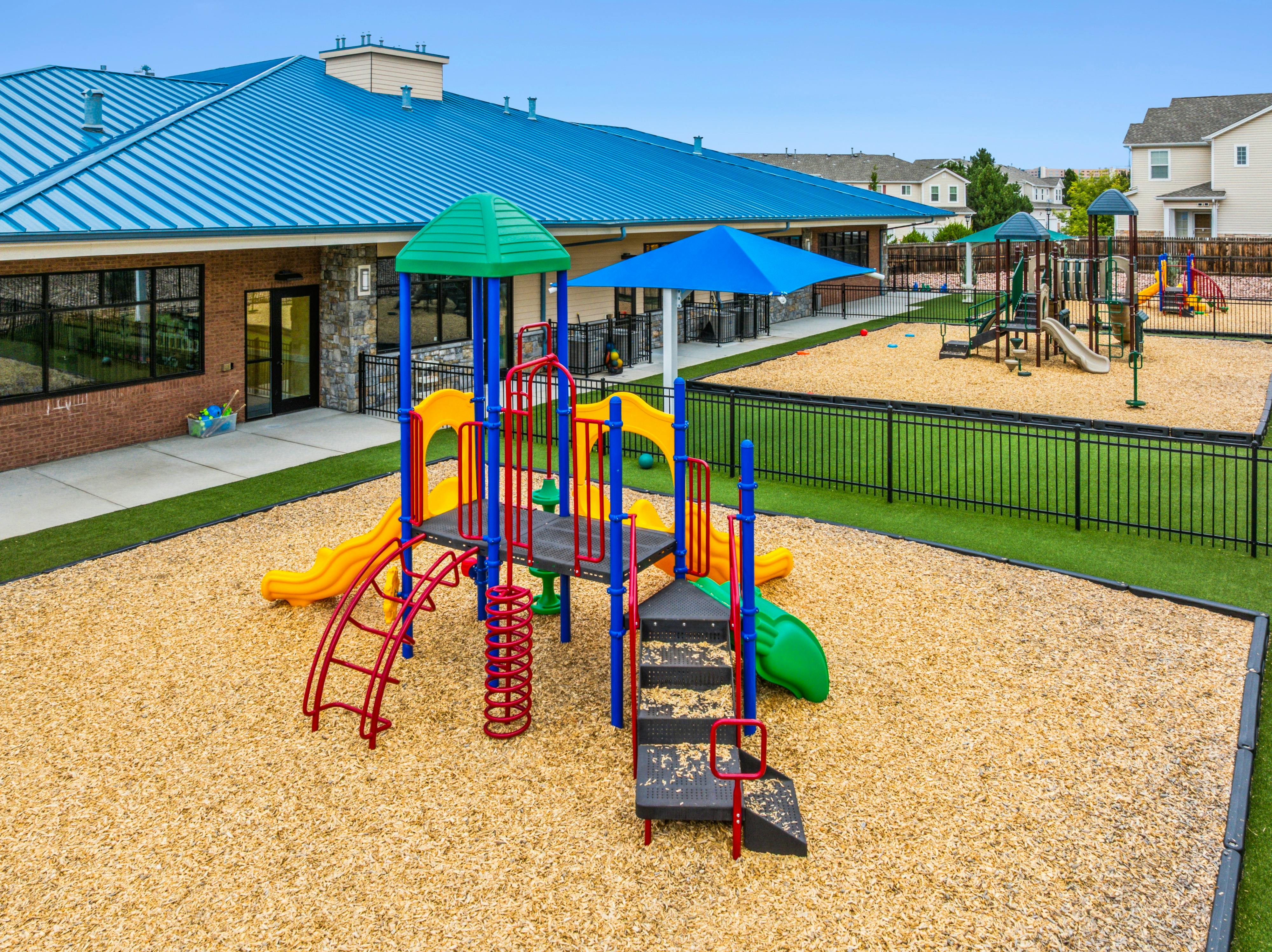 Outdoor playground with multiple colorful play structures and wood chip ground cover