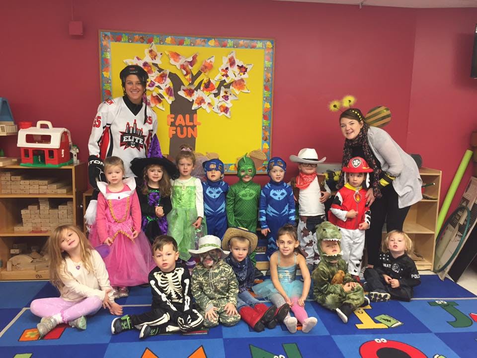 Two adults and many children in various costumes posing for a photo