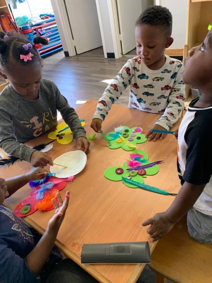 Children at a table making crafts with colorful decorations