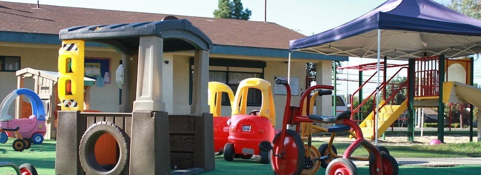 Playground with playhouse, ride-on toys, and climbing structure