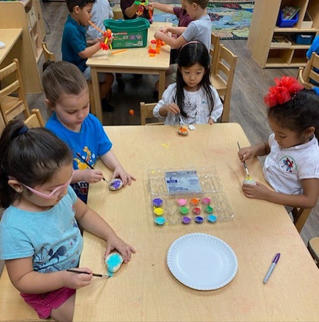 Children painting rocks at a table