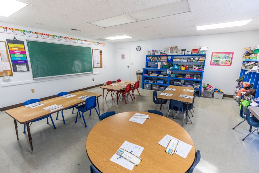 Empty classroom with tables, chairs, and a chalkboard