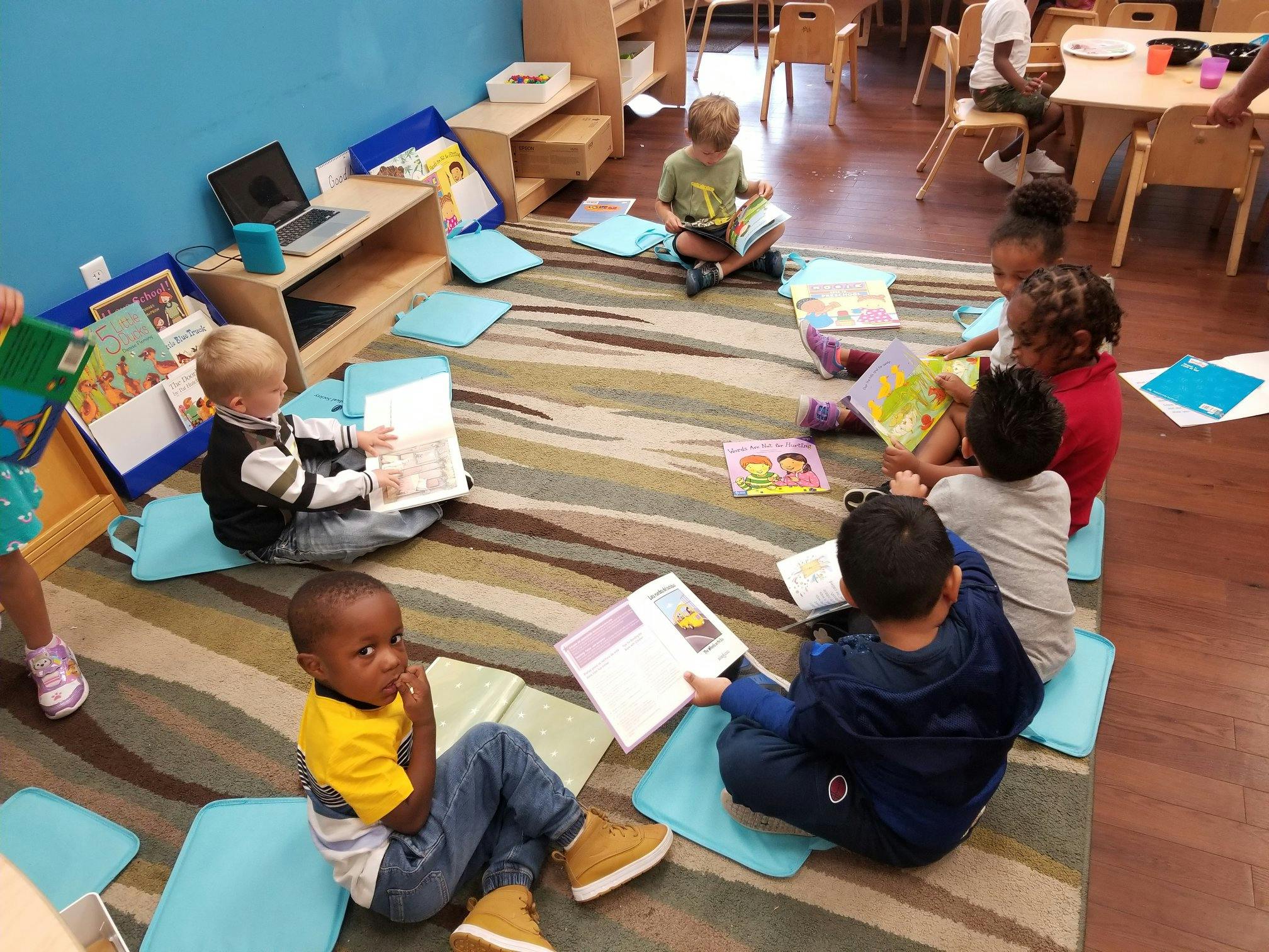 Children sitting on a rug reading books in a classroom