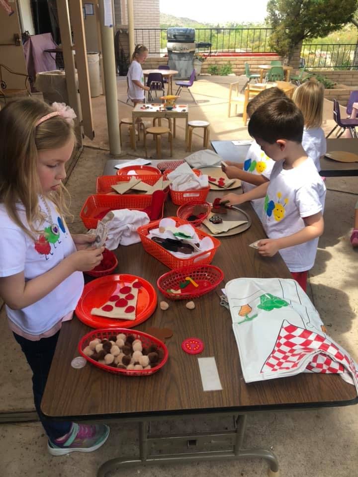 Children making crafts at a table outdoors