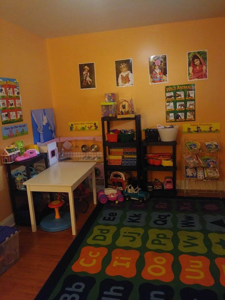 Playroom with a table, shelves of toys, and an alphabet rug