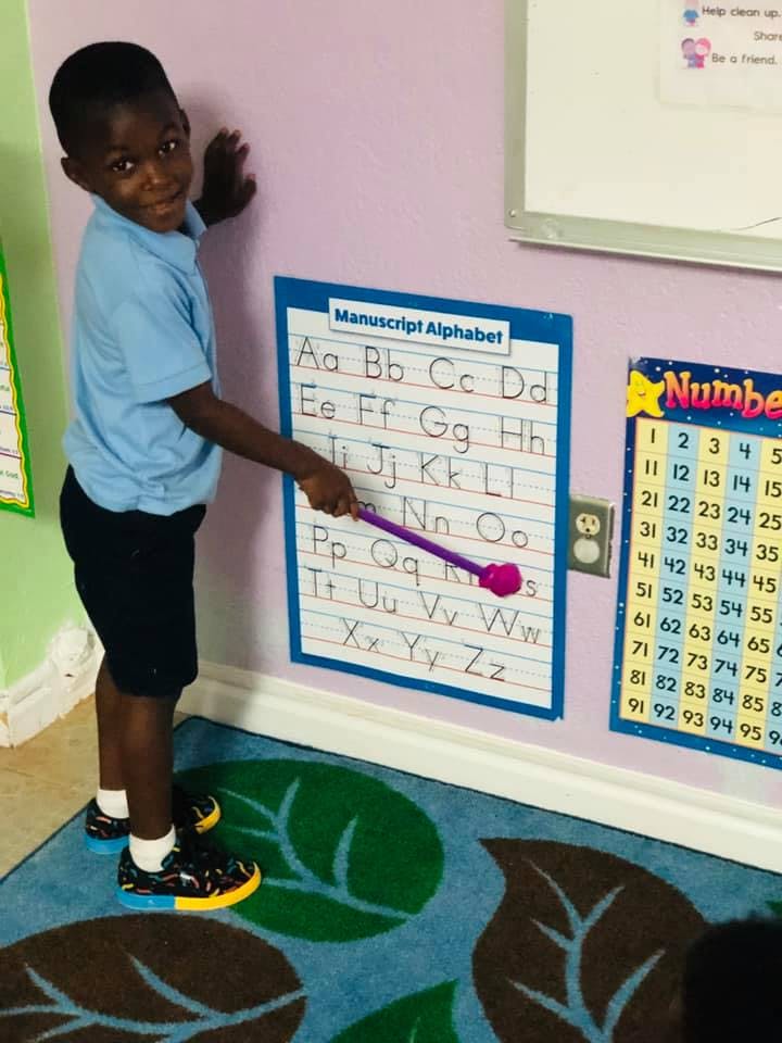 Child pointing to an alphabet chart with a pointer