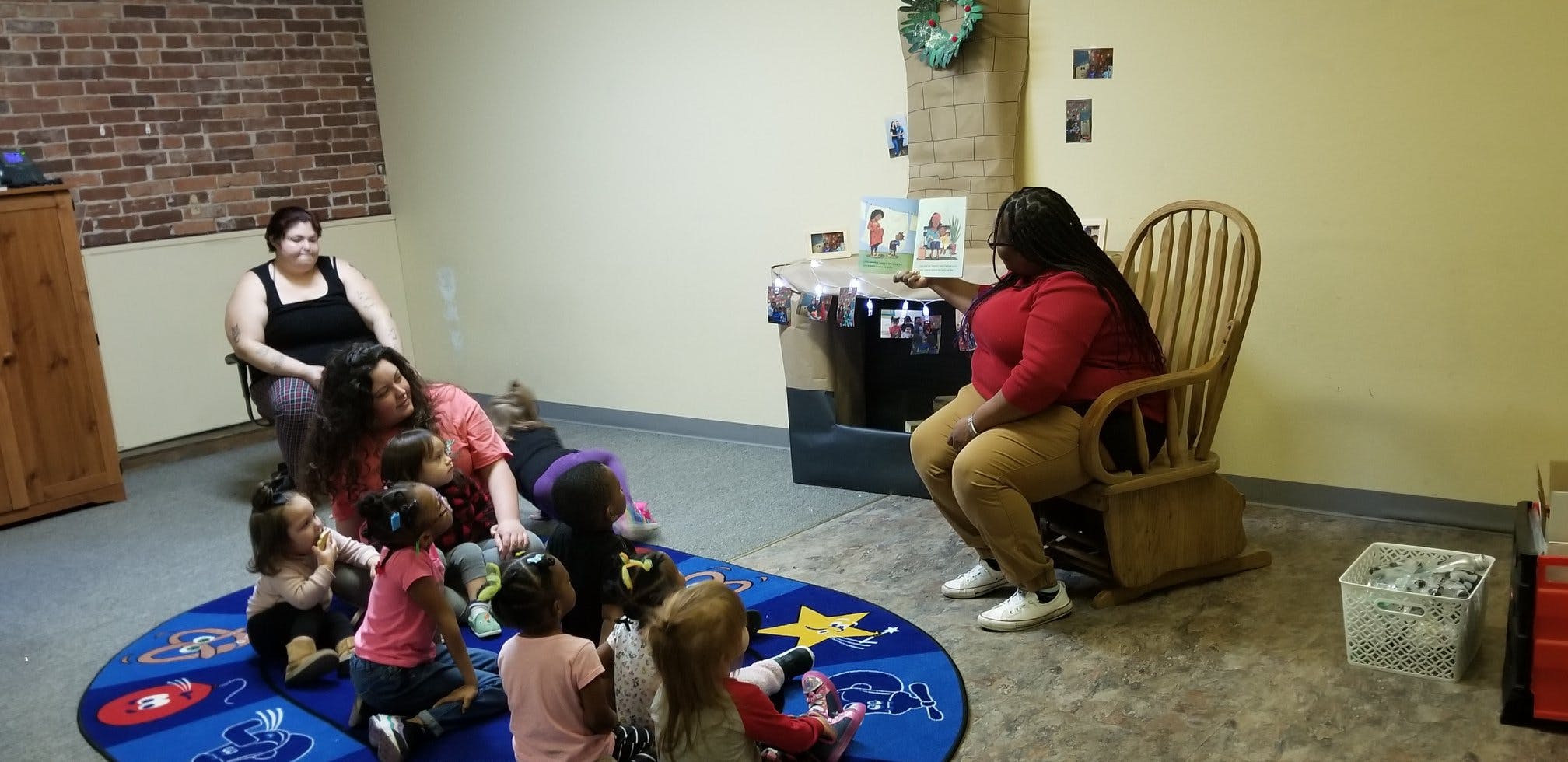 People and children gathered on a rug in a room