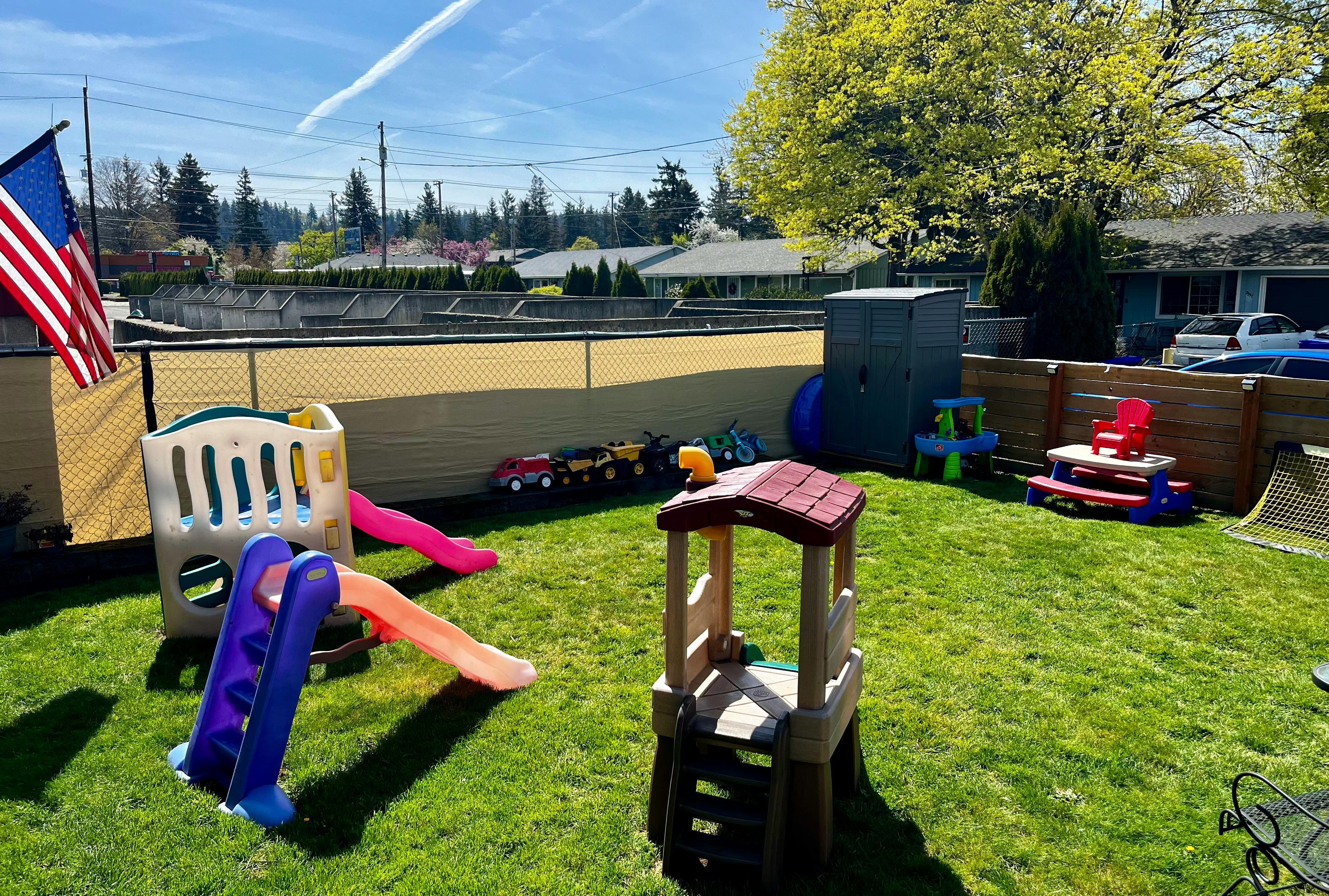 Backyard with children's play structures and an American flag
